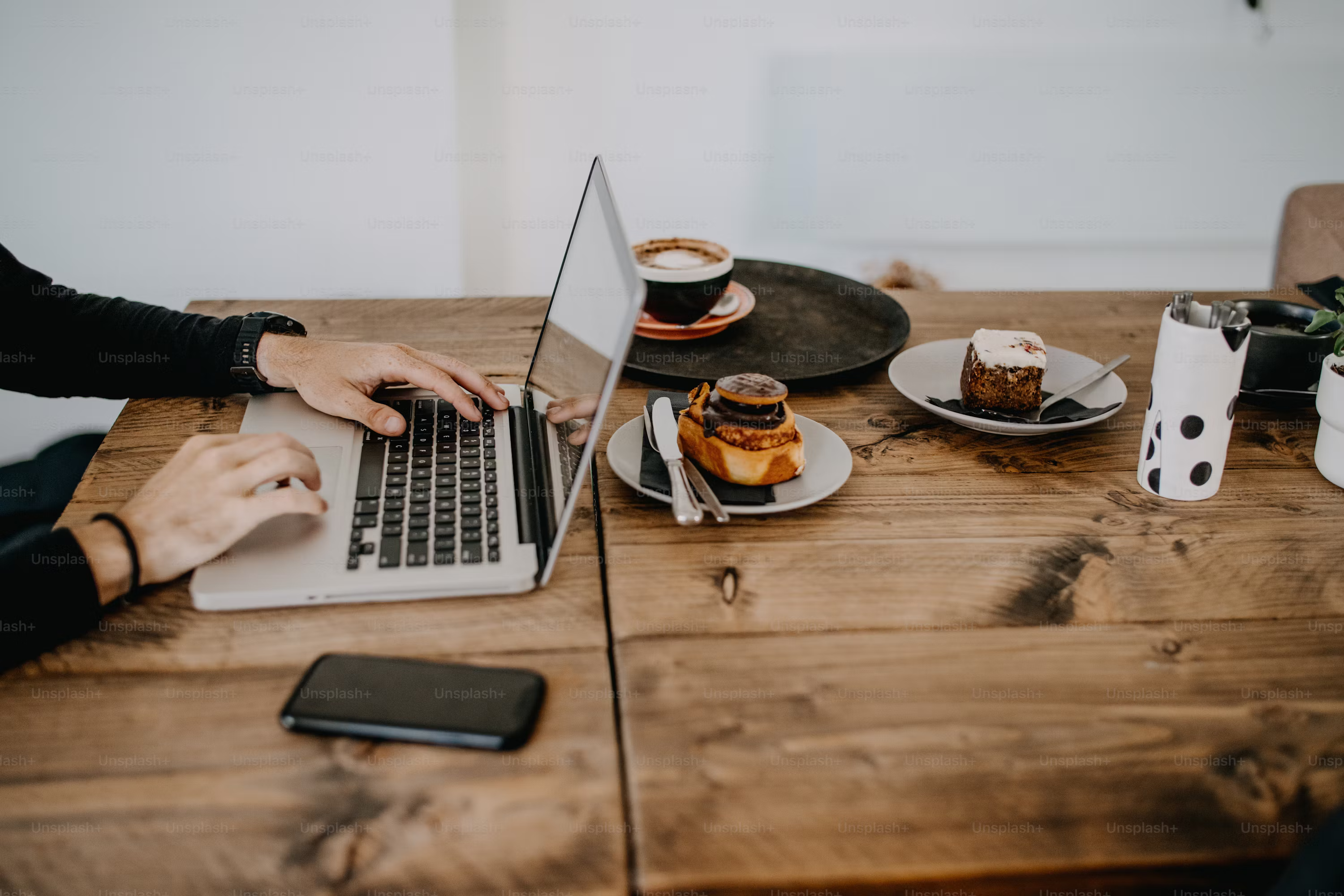 Photo of a laptop and coffee cup on a wooden table inside a cozy Yogyakarta cafe